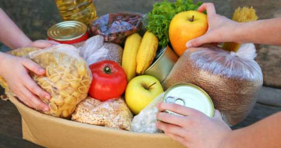 Donation box with food on old wooden background